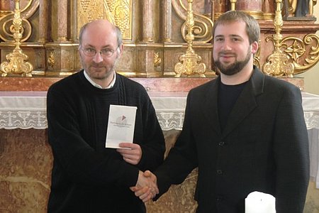 Dorfhaus-Leiter Harald Gretz (rechts) überreicht P. Daniel den gesammelten Geldbetrag.