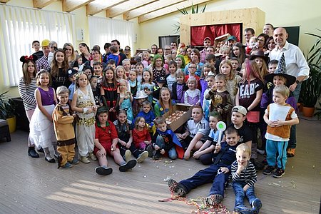 Gruppenfoto mit allen Kindern vor dem Kasperltheater